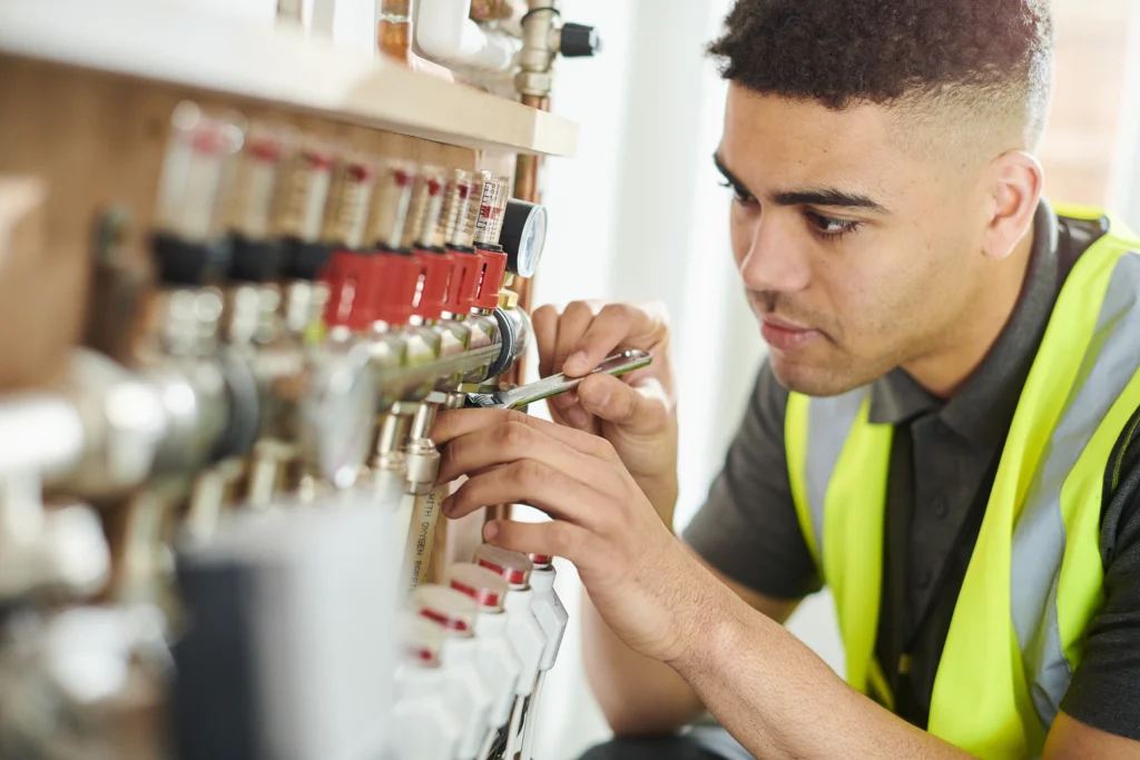 A man in a safety vest is diligently working on a valve, ensuring proper maintenance and safety protocols are followed.